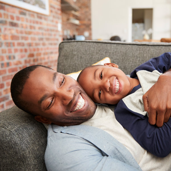 father and son laughing on couch